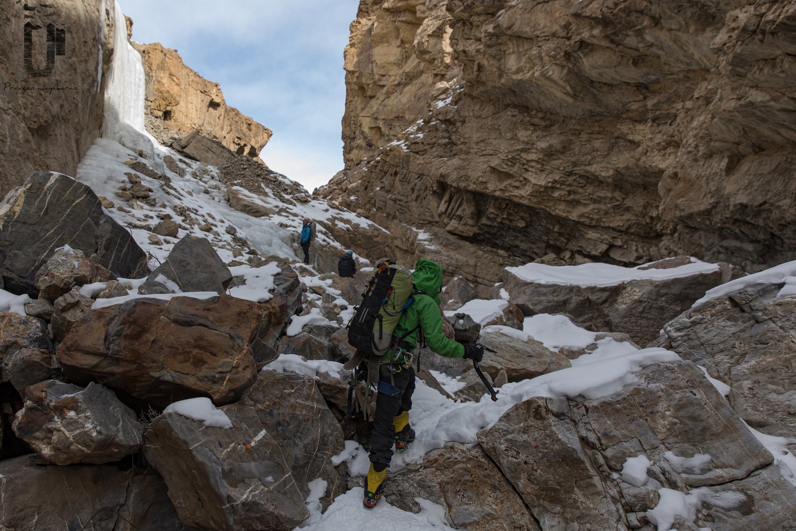 Climbers approaching ice wall through boulder field in Spiti Valley